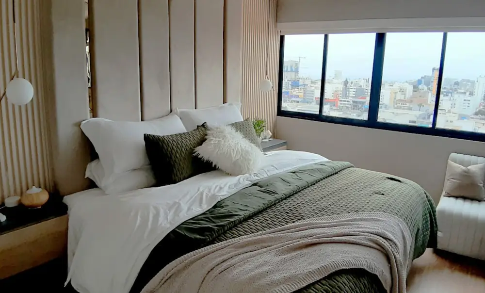 Dormitorio para Airbnb diseñado por Anni, con cabecero tapizado y vista a la ciudad